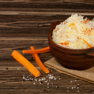 Fermented Cabbage. Sauerkraut With Carrots In Clay Bowl On Woode Fermented Cabbage. Sauerkraut With Carrots In Clay Bowl On Woode