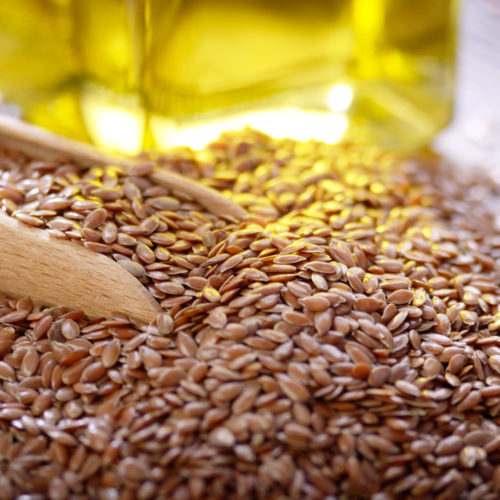 Flax Oil And Raw Seeds In Wooden Scoop On Kitchen Table Closeup Flax Oil And Raw Seeds In Wooden Scoop On Kitchen Table Closeup