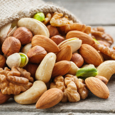 Mix Of Different Nuts In A Wooden Cup Against The Background Of Fabric From Burlap. Nuts As Structure And Background, Macro. Top View. Mix Of Different Nuts In A Wooden Cup Against The Background Of Fabric From Burlap. Nuts As Structure And Background, Macro. Top View.