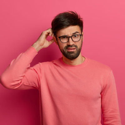 Serious Bearded Young Man Scratches Head, Thinks Deeply About How To Solve Problem, Makes Decision, Wears Optical Glasses, Poses Indoor Against Rosy Background, Makes Up Plan, Has Bad Memory Serious Bearded Young Man Scratches Head, Thinks Deeply About How To Solve Problem, Makes Decision, Wears Optical Glasses, Poses Indoor Against Rosy Background, Makes Up Plan, Has Bad Memory